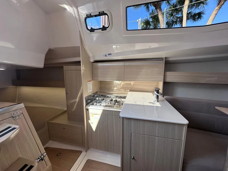 Slide: The Image of Modern Maxus 26 yacht interior with kitchenette, featuring stove, sink, and wood cabinetry, 2025 model. - 12