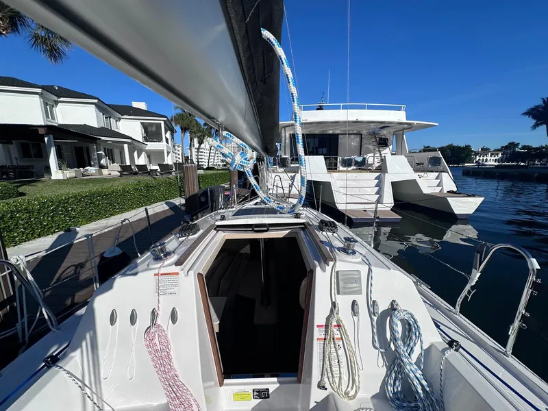 Slide: The Image of 2025 Maxus 26 sailboat docked near waterfront homes under clear blue sky. - 2