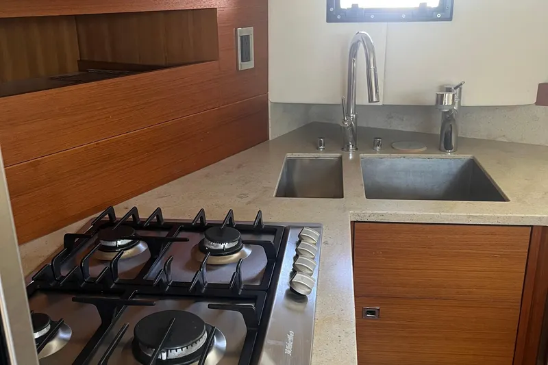 Slide: The Image of Modern kitchen in 2015 Gunboat 57' yacht with stove, dual sinks, and wooden cabinetry. - 13