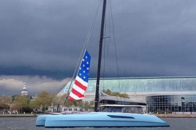 Slide: The Image of Gunboat 57' catamaran, 2015 model, with American flag, docked near modern building. - 4