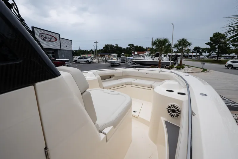 Slide: The Image of 2026 Scout 288 LXF boat interior with seating and speaker, parked near dealership. - 28
