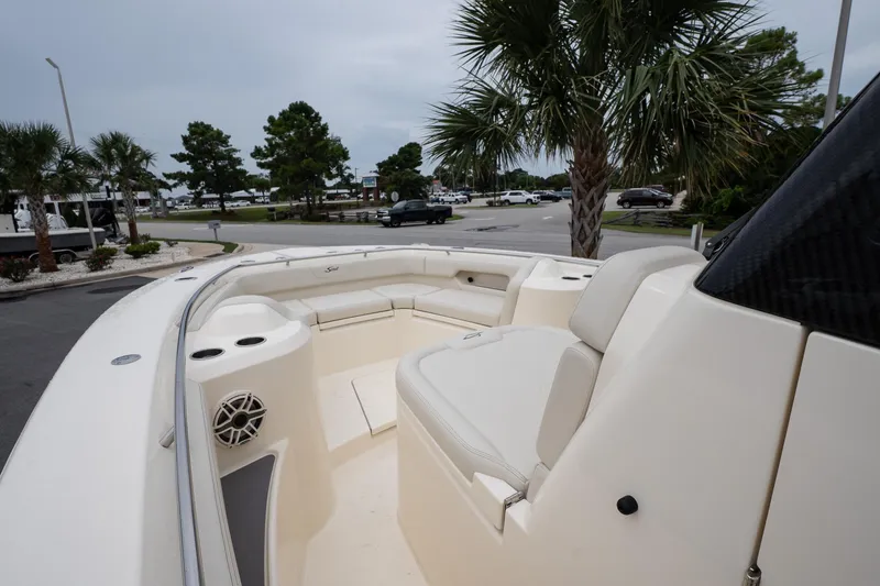 Slide: The Image of 2026 Scout 288 LXF boat interior with seating, palm trees, and parking lot in background. - 41