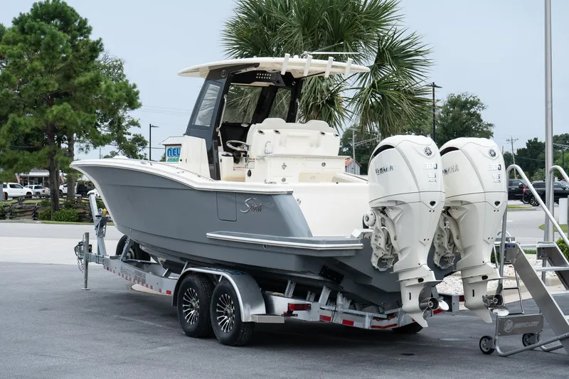 Slide: The Image of 2026 Scout 288 LXF boat on trailer with dual Yamaha engines, parked outdoors. - 5