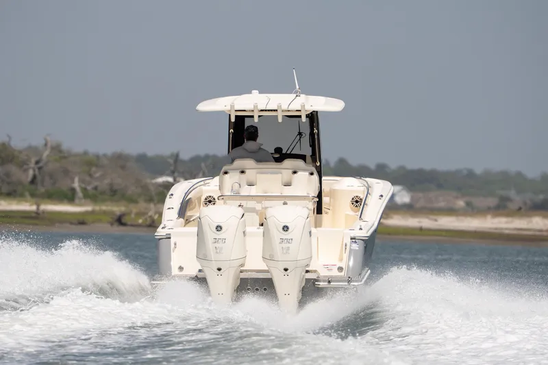 Slide: The Image of 2026 Scout 288 LXF boat cruising on water, rear view with dual engines. - 53
