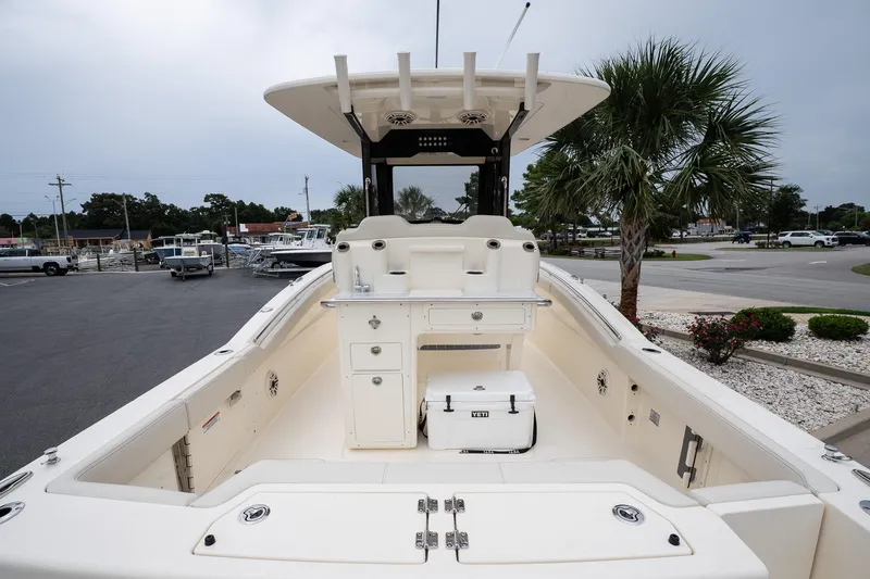 Slide: The Image of 2026 Scout 288 LXF boat interior with seating, storage, and cooler, parked near palm trees. - 8