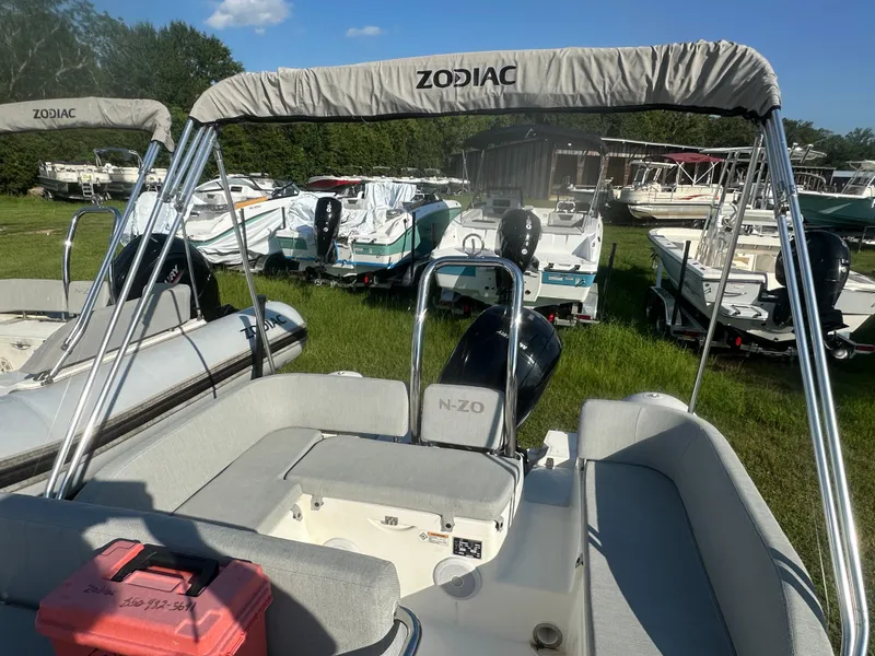 Slide: The Image of 2023 Zodiac N-ZO 680 boat with canopy, parked among other boats on grass. - 10
