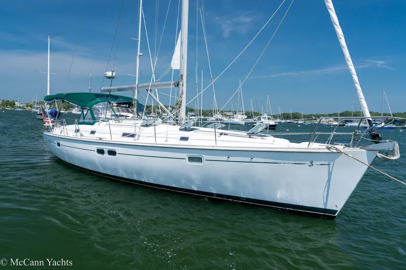 Slide: The Image of 1999 Beneteau 411 sailboat anchored in a marina under clear blue skies. - 0