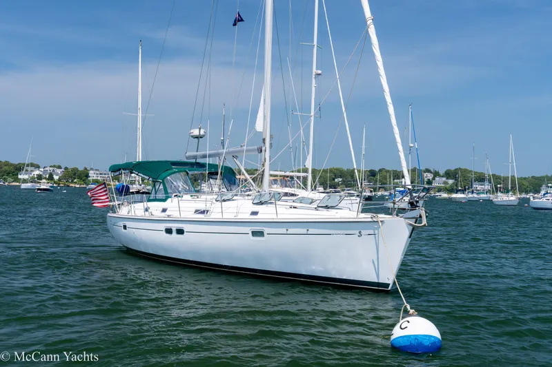 Slide: The Image of 1999 Beneteau 411 sailboat anchored in a scenic harbor with clear skies. - 1