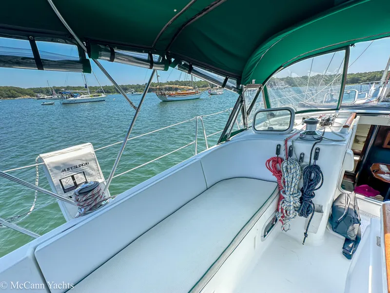 Slide: The Image of Cockpit of 1999 Beneteau 411 sailboat with green canopy, ropes, and scenic harbor view. - 12
