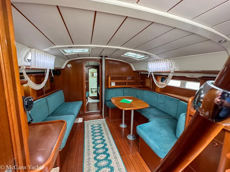 Slide: The Image of Interior of a 1999 Beneteau 411 yacht with teal seating and wooden finishes. - 16
