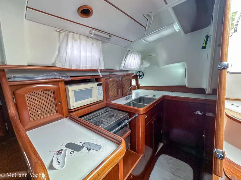Slide: The Image of Interior of a 1999 Beneteau 411 yacht kitchen with wood cabinetry and appliances. - 17