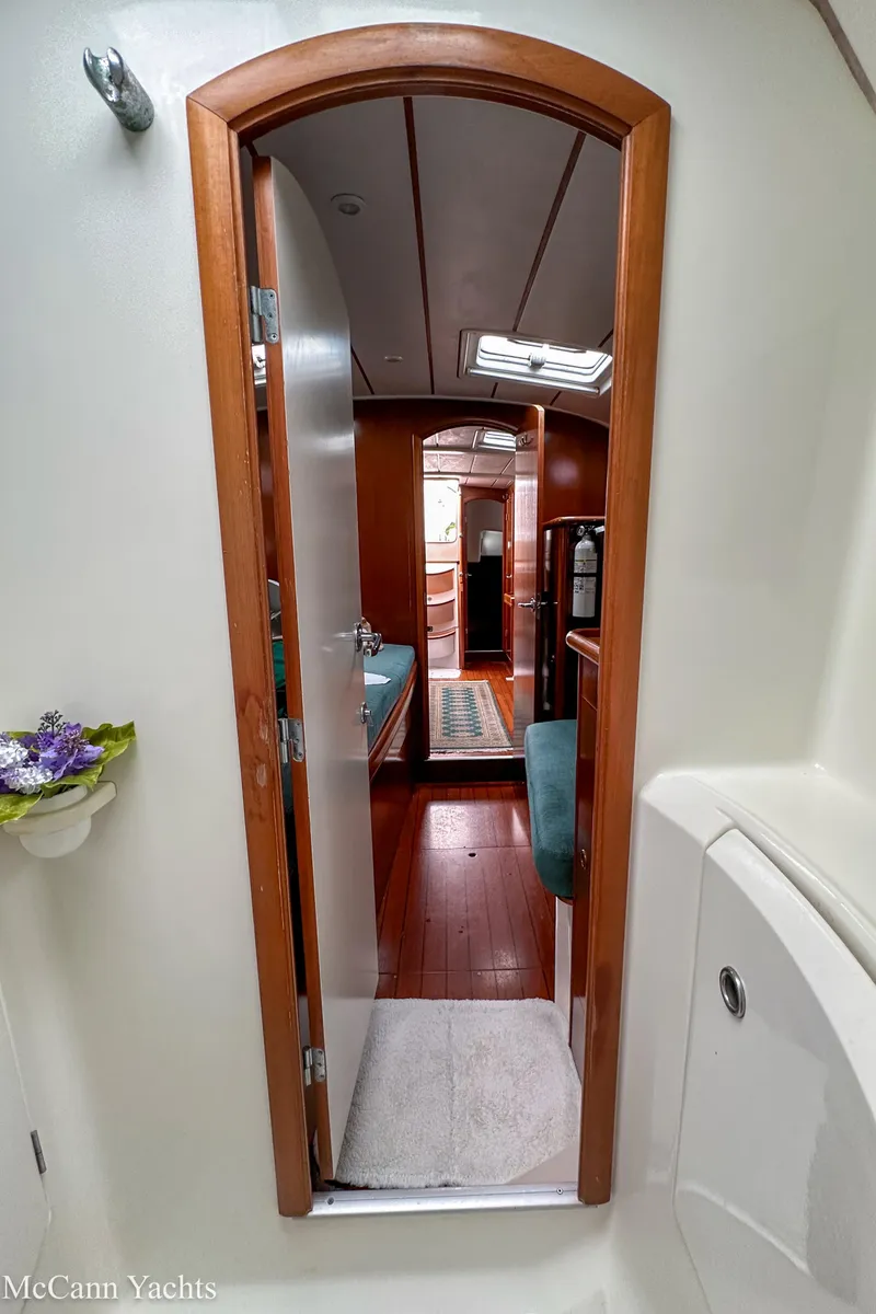 Slide: The Image of Interior view of 1999 Beneteau 411 yacht, featuring wooden door and cozy cabin space. - 27