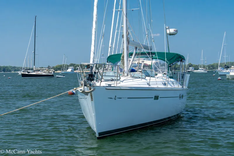 Slide: The Image of 1999 Beneteau 411 sailboat anchored in a serene harbor with clear blue skies. - 3