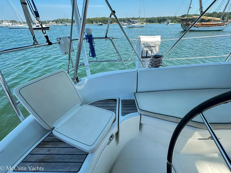 Slide: The Image of Cockpit view of 1999 Beneteau 411 sailboat, featuring seating and steering wheel, anchored in a marina. - 36