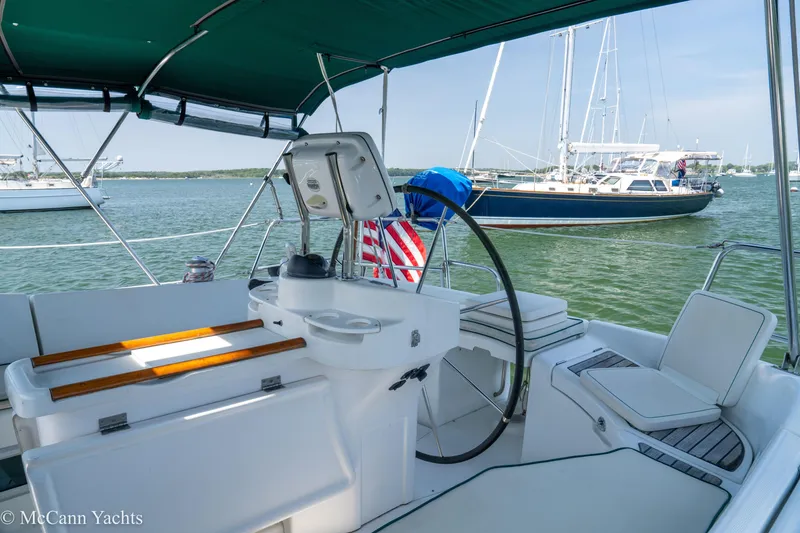 Slide: The Image of Cockpit view of a 1999 Beneteau 411 sailboat with a green canopy and scenic marina backdrop. - 39