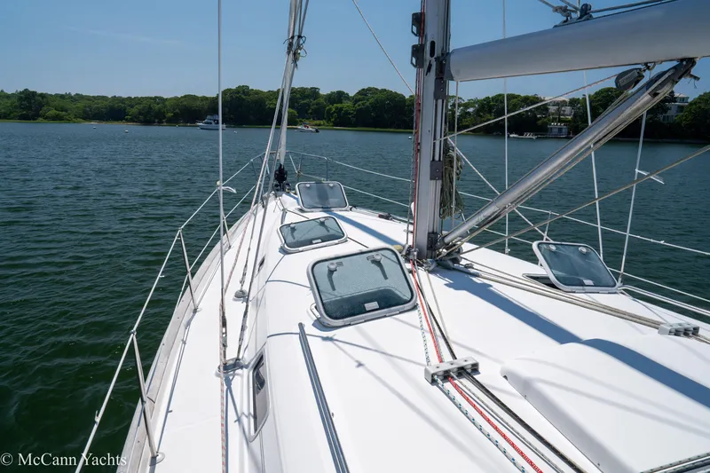 Slide: The Image of Sailing on a 1999 Beneteau 411 yacht, calm waters, clear sky, lush shoreline. - 40