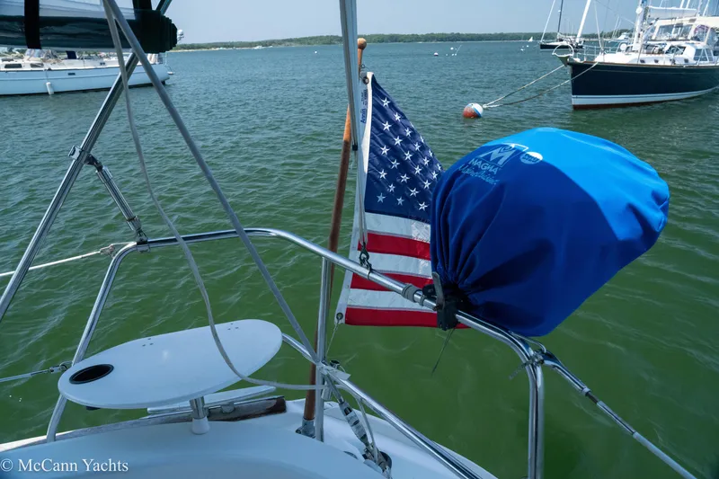 Slide: The Image of Sailboat Beneteau 411 (1999) with American flag and covered equipment on deck. - 46