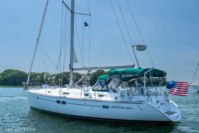 Slide: The Image of 1999 Beneteau 411 sailboat on calm water with American flag, clear sky background. - 5