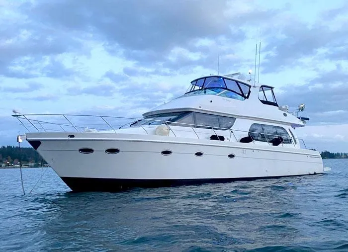 The Image of 2004 Carver 560 Voyager PH yacht on calm water under cloudy sky. - 0