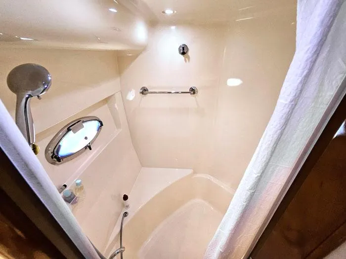 Slide: The Image of Shower area in 2004 Carver 560 Voyager PH yacht, featuring modern fixtures and porthole. - 18