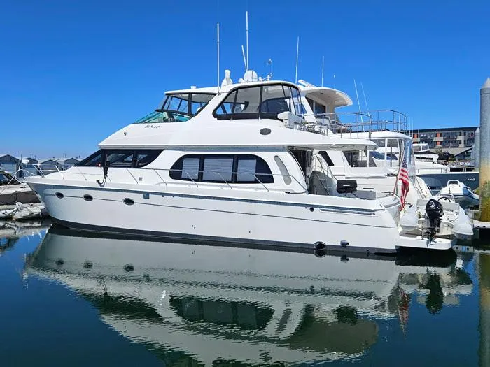Slide: The Image of 2004 Carver 560 Voyager PH yacht docked in marina, reflecting on calm water. - 2