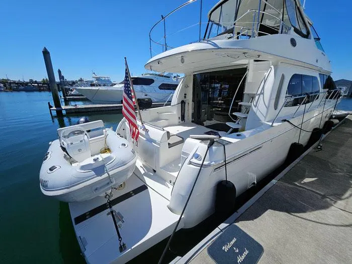 Slide: The Image of 2004 Carver 560 Voyager PH yacht docked with American flag and small boat. - 3