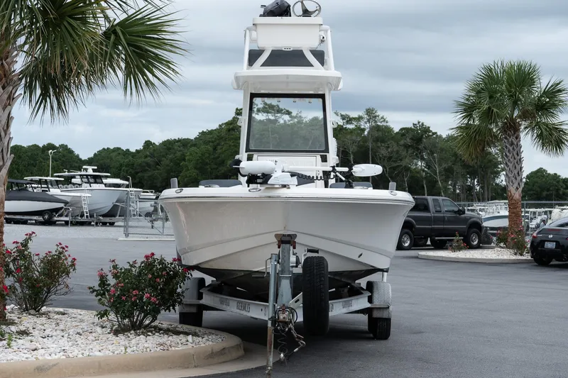 Slide: The Image of 2019 Robalo 246 Cayman SD boat on trailer, surrounded by palm trees and parked vehicles. - 13