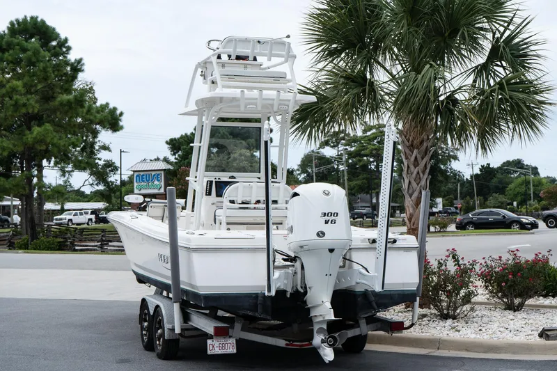 Slide: The Image of 2019 Robalo 246 Cayman SD boat on trailer, parked near palm tree and road. - 14