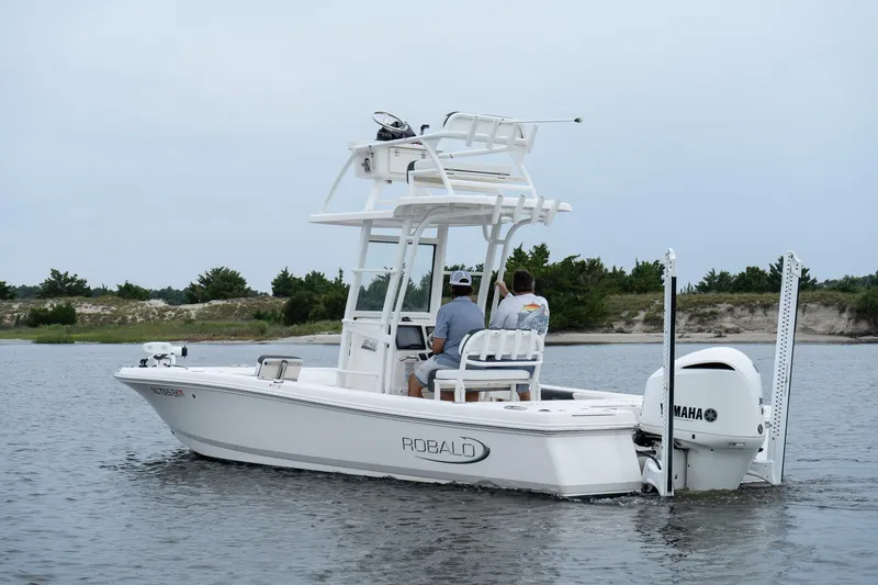 Slide: The Image of 2019 Robalo 246 Cayman SD boat on calm water with two people onboard. - 2