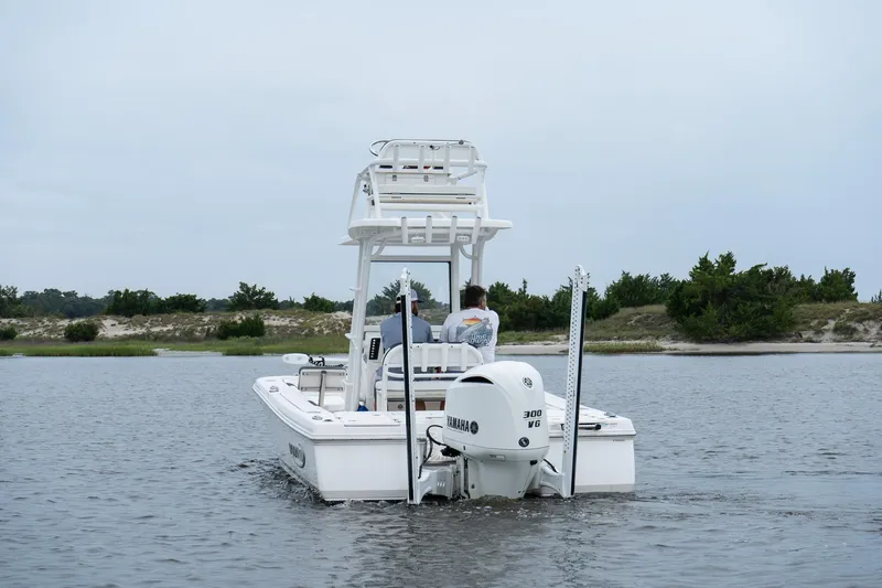 Slide: The Image of 2019 Robalo 246 Cayman SD boat cruising on calm water near a sandy shoreline. - 3