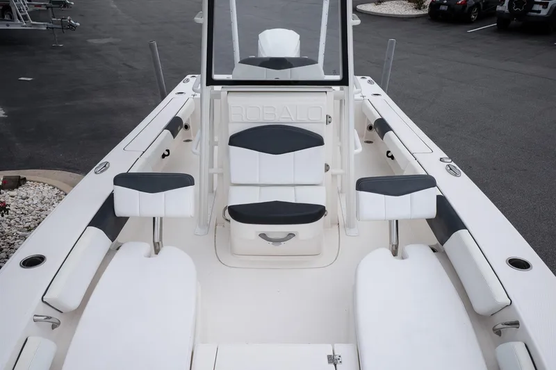 Slide: The Image of 2019 Robalo 246 Cayman SD boat interior with seating and console, parked on asphalt. - 33