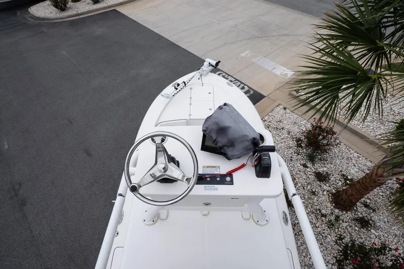 Slide: The Image of 2019 Robalo 246 Cayman SD boat helm with steering wheel and controls, parked near palm trees. - 37