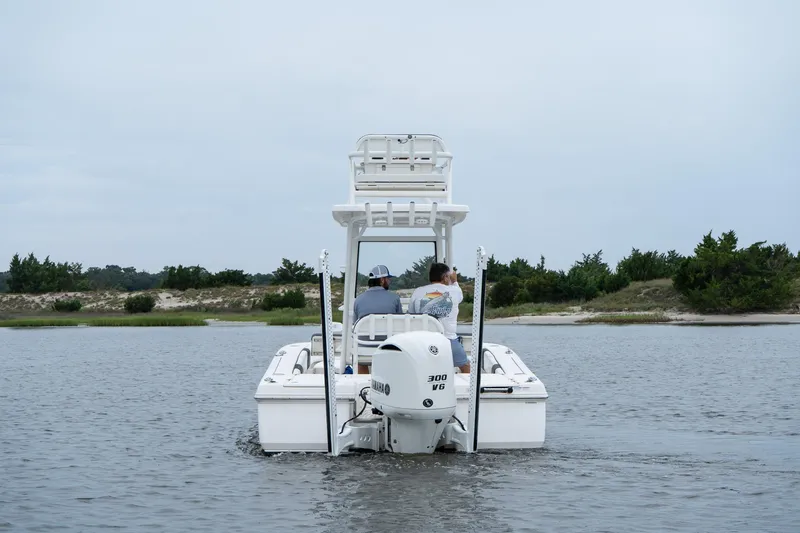Slide: The Image of 2019 Robalo 246 Cayman SD boat cruising on calm water near a sandy shoreline. - 4