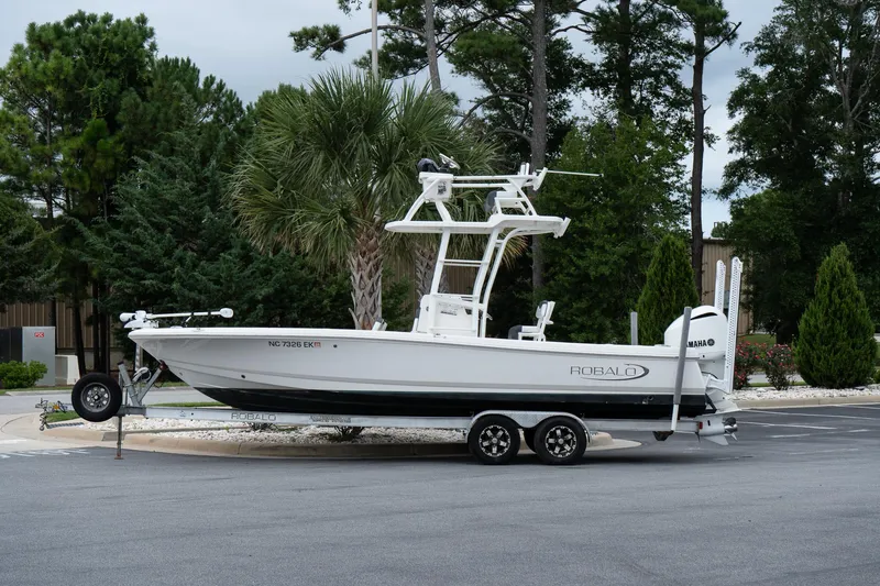 Slide: The Image of 2019 Robalo 246 Cayman SD boat on trailer, parked near trees. - 9