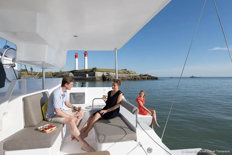 Slide: The Image of People relaxing on a NEEL 47 trimaran, near lighthouses, enjoying a sunny day at sea. - 18
