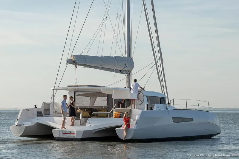 Slide: The Image of 2025 NEEL 47 trimaran sailing on calm waters with people on deck. - 2