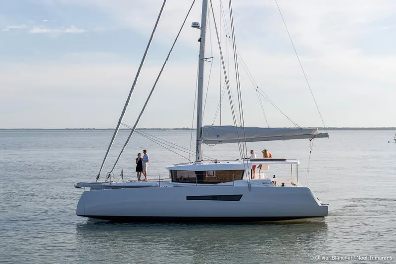 Slide: The Image of 2025 NEEL 47 trimaran sailing on calm waters under a clear sky. - 5