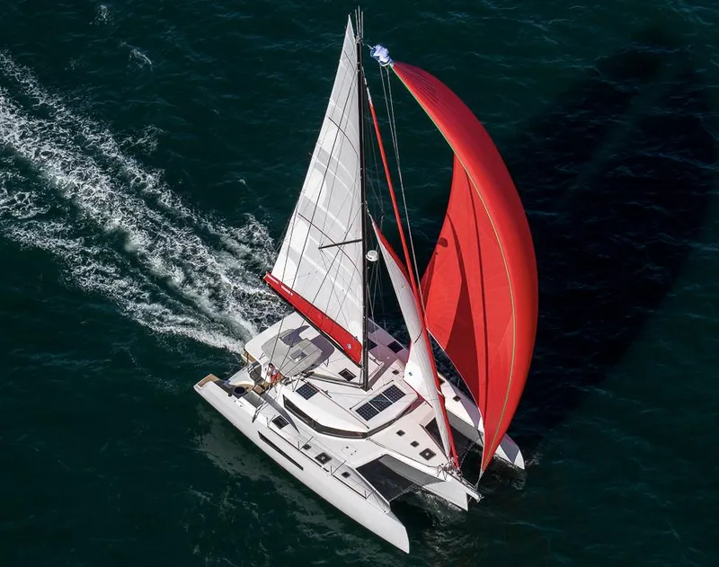 Slide: The Image of Aerial view of 2025 NEEL 47 trimaran sailing with red and white sails. - 1