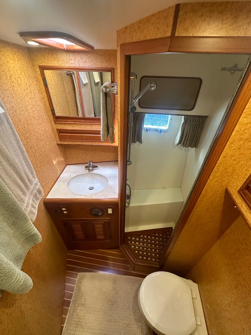 Slide: The Image of 2000 Offshore Yachts Pilothouse bathroom with shower, sink, and toilet. - 15