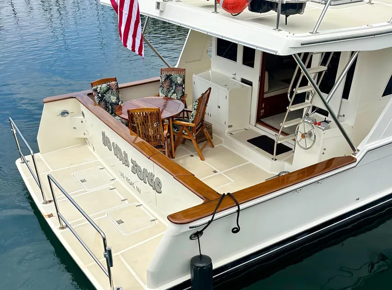 Slide: The Image of 2000 Offshore Yachts Pilothouse with deck seating, American flag, and elegant wood accents. - 19