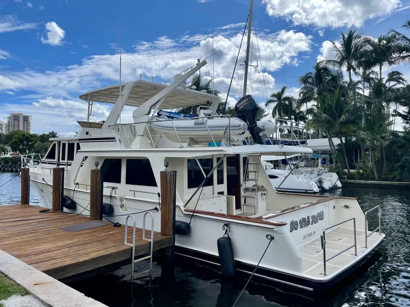 Slide: The Image of 2000 Offshore Yachts Pilothouse docked, surrounded by palm trees and a clear blue sky. - 3