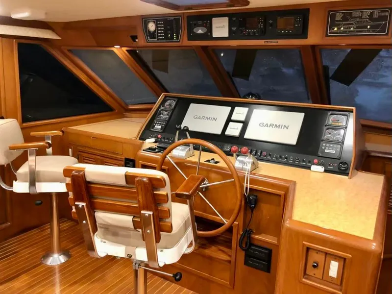 Slide: The Image of Pilothouse interior of 2000 Offshore Yachts model, featuring Garmin navigation systems and wooden helm. - 5