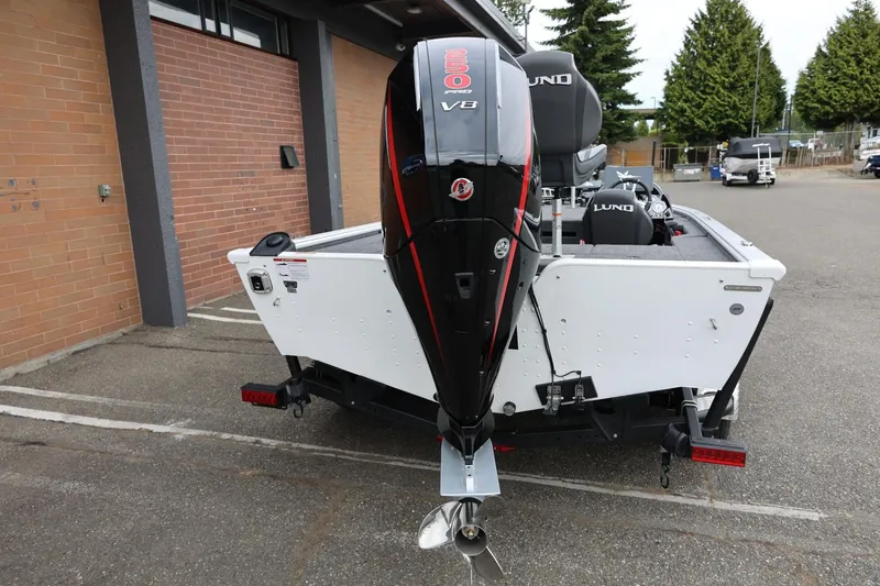 Slide: The Image of 2026 Lund 2075 Pro-V Bass XS boat with powerful outboard motor, parked outdoors. - 12