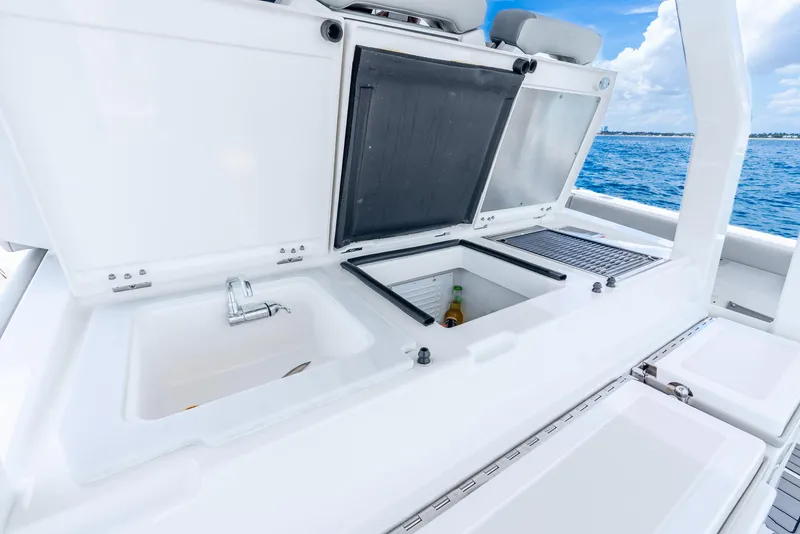 Slide: The Image of 2024 Pursuit S 358 Sport boat with open storage compartments and sink, ocean view. - 48