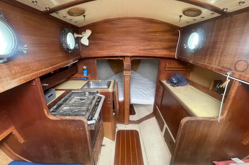 Slide: The Image of Interior of a 1980 Falmouth Cutter sailboat with wooden cabinetry and compact kitchen. - 10