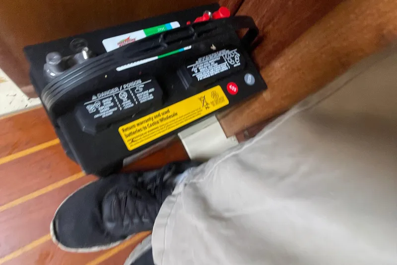 Slide: The Image of Battery installation on 1980 Falmouth Cutter boat, with person wearing black shoes and beige pants. - 16