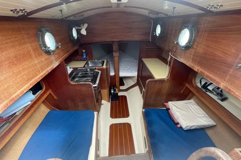 Slide: The Image of 1980 Falmouth Cutter interior with wood paneling, portholes, and compact kitchen area. - 6