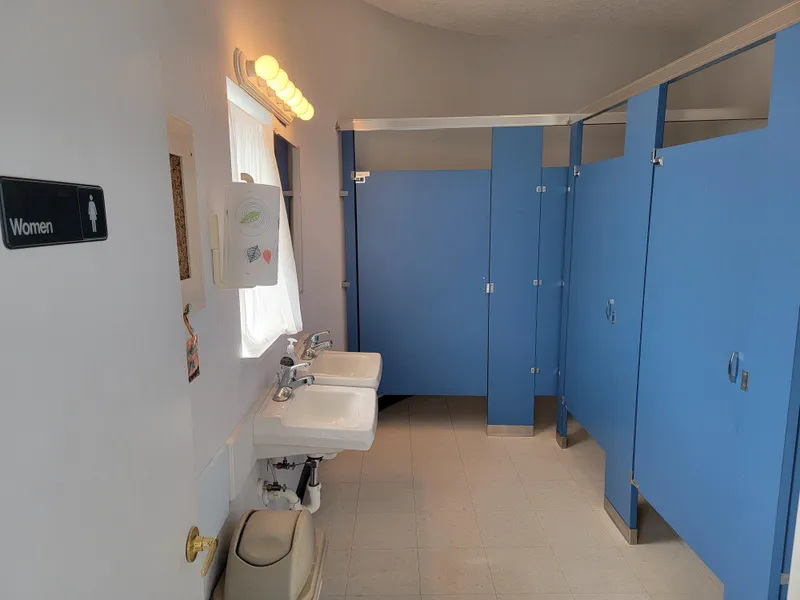 Slide: The Image of Women's restroom with blue stalls and white sinks in a 2003 custom floating home. - 13