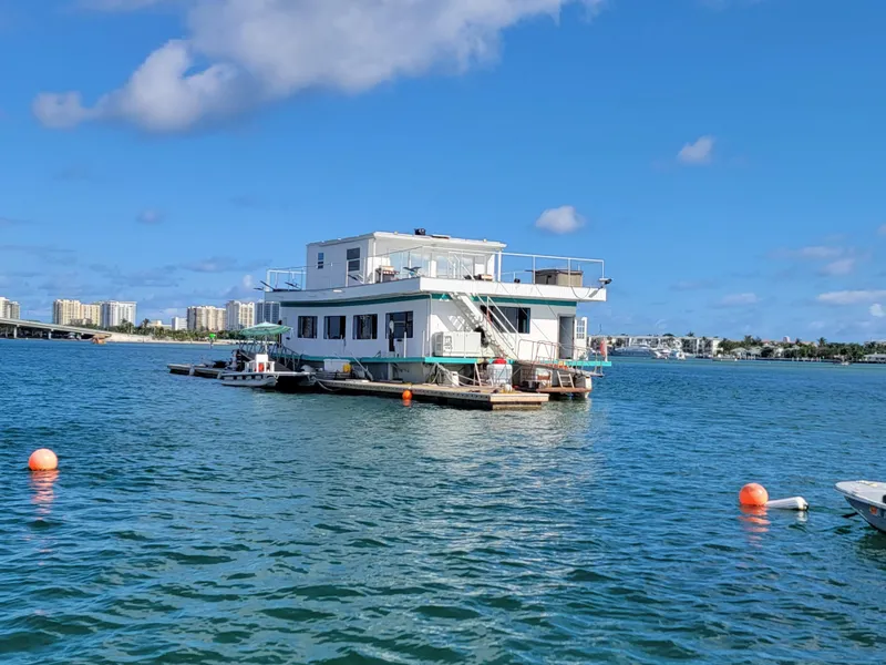 Slide: The Image of Custom 2003 floating home on water, clear sky, cityscape in background. - 8