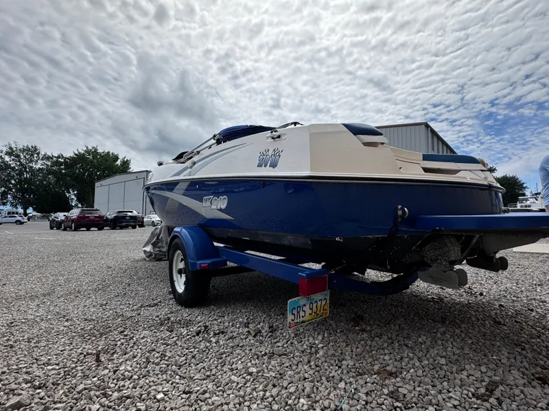 The Image of 2003 Yamaha Boats 210LX on trailer, parked on gravel under cloudy sky. - 0